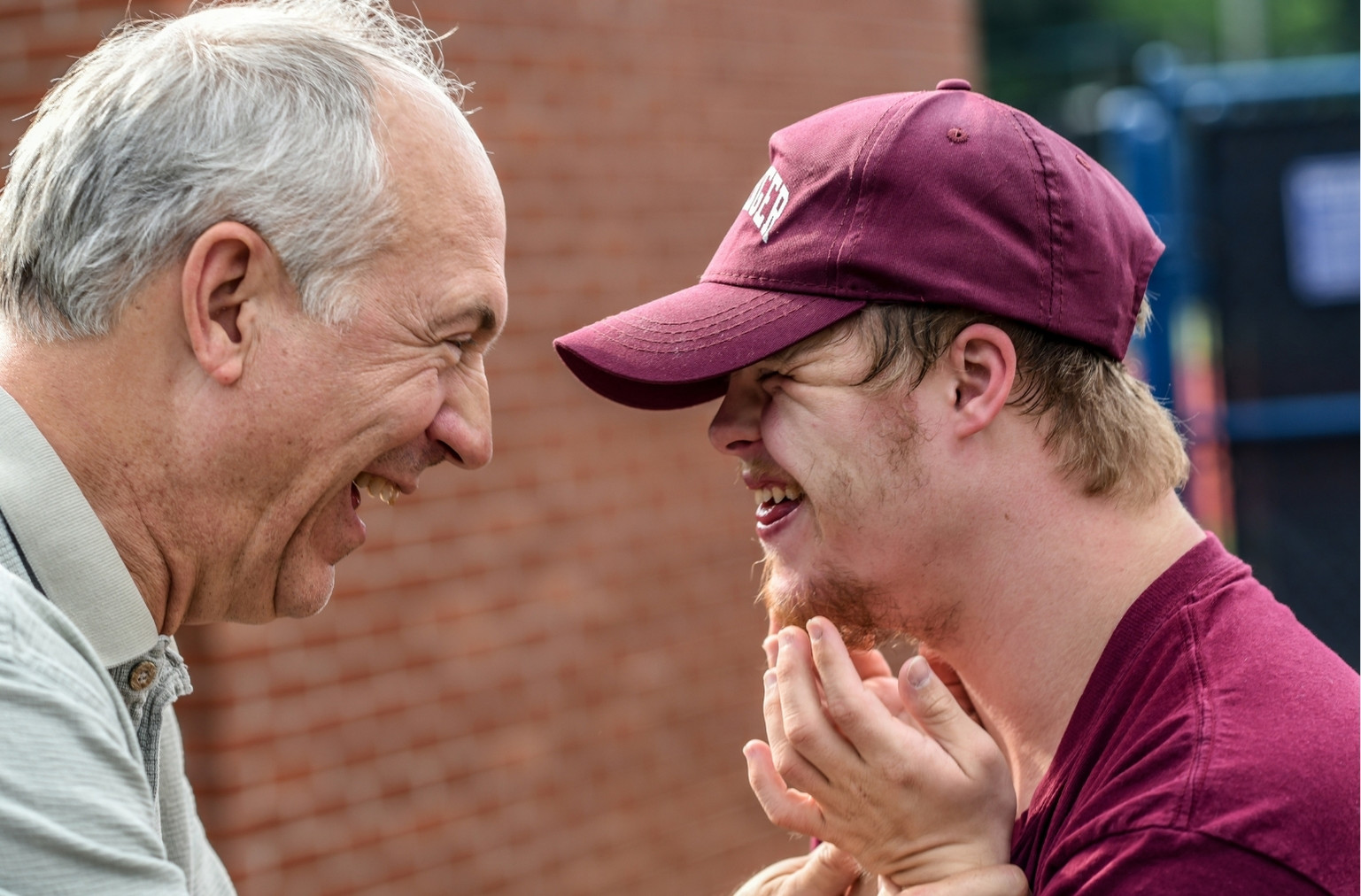 older man smiling and laughing with special needs boy